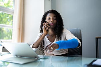 How does workers comp work: woman with a cast on her arm talking on the phone