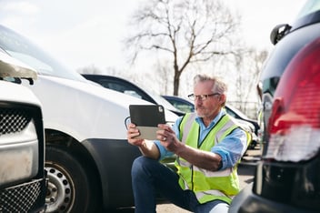 Claims administration: person using a tablet to take a photo of a car